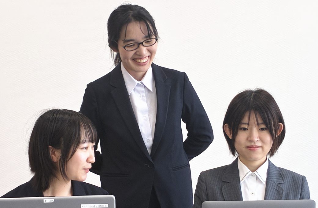 ノートパソコンに向かう2人に助言するICSのメンバー
